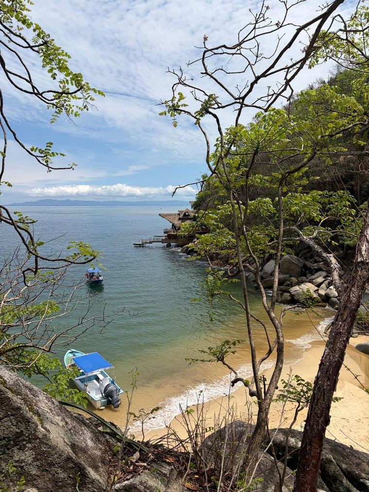 Secluded Puerto Vallarta cove with boats and rocks along the coastline